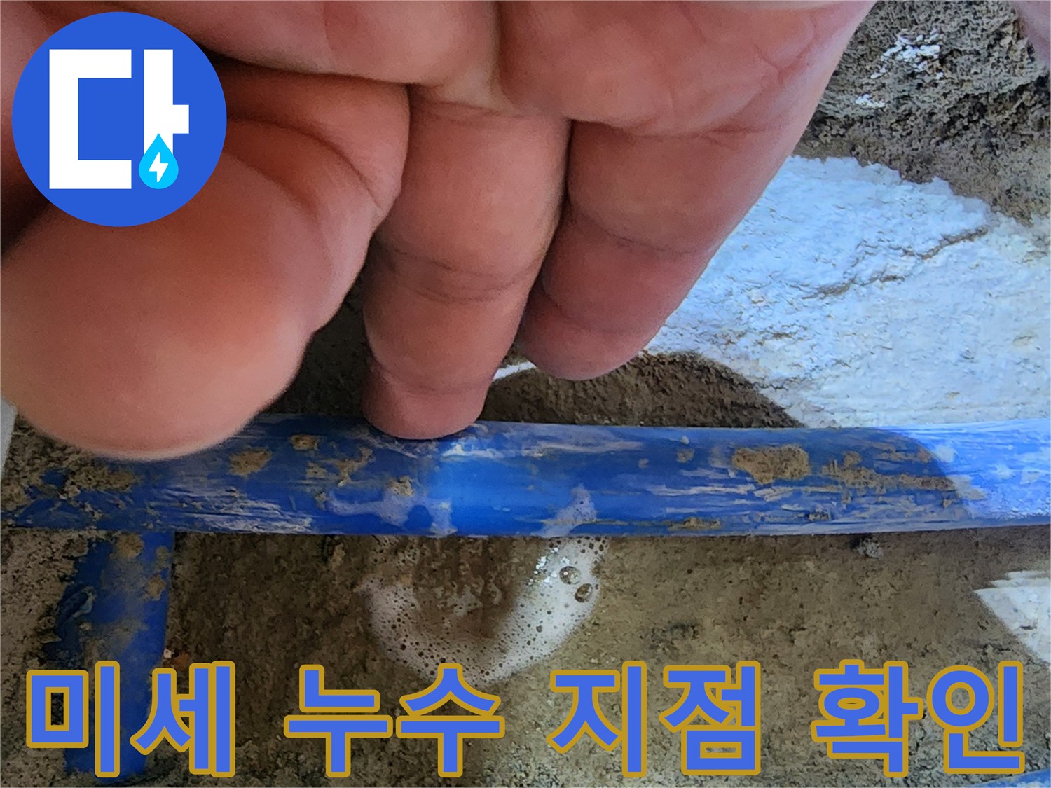 엔지니어의 손가락이-파란색 수도관의-미세한 누수 지점을 가리키며-거품으로 누수를-확인하는 모습