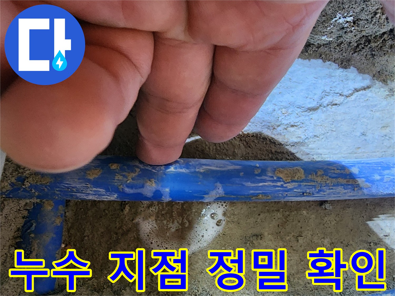 전문가의 손이-파란색 수도관의-누수 지점을 가리키며-거품으로 누수를-명확히 보여주는 사진