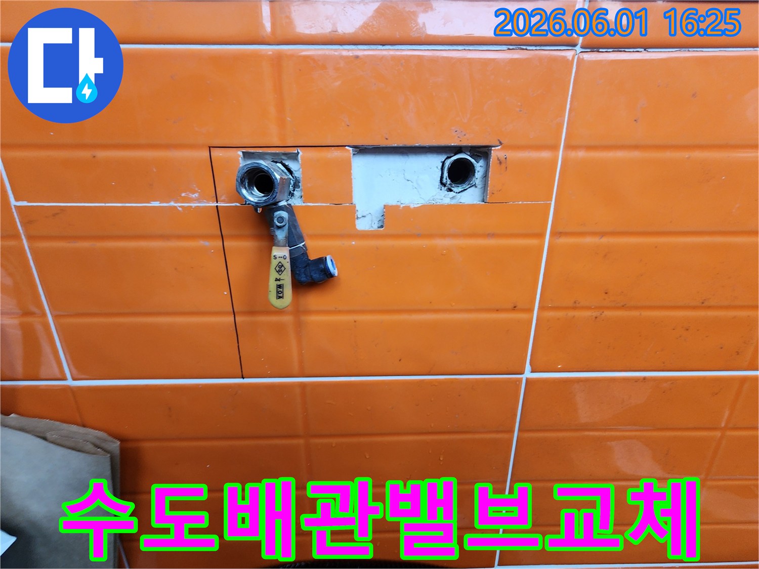 오렌지색-타일이-부분적으로-제거된-곳에-새로운-수도-밸브가-설치된-배관-수리-과정을-담은-사진입니다.