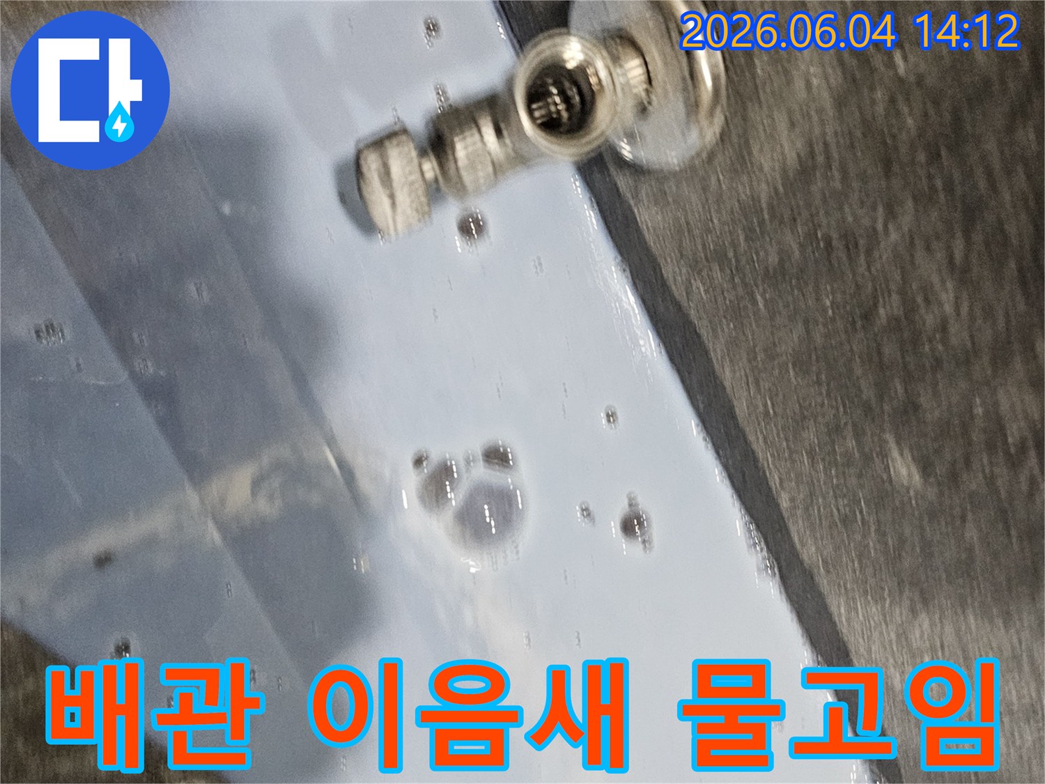 배관-이음새-부분에서-발생한-누수로-인해-주변에-물이-고여있는-모습을-보여주는-현장-사진입니다.