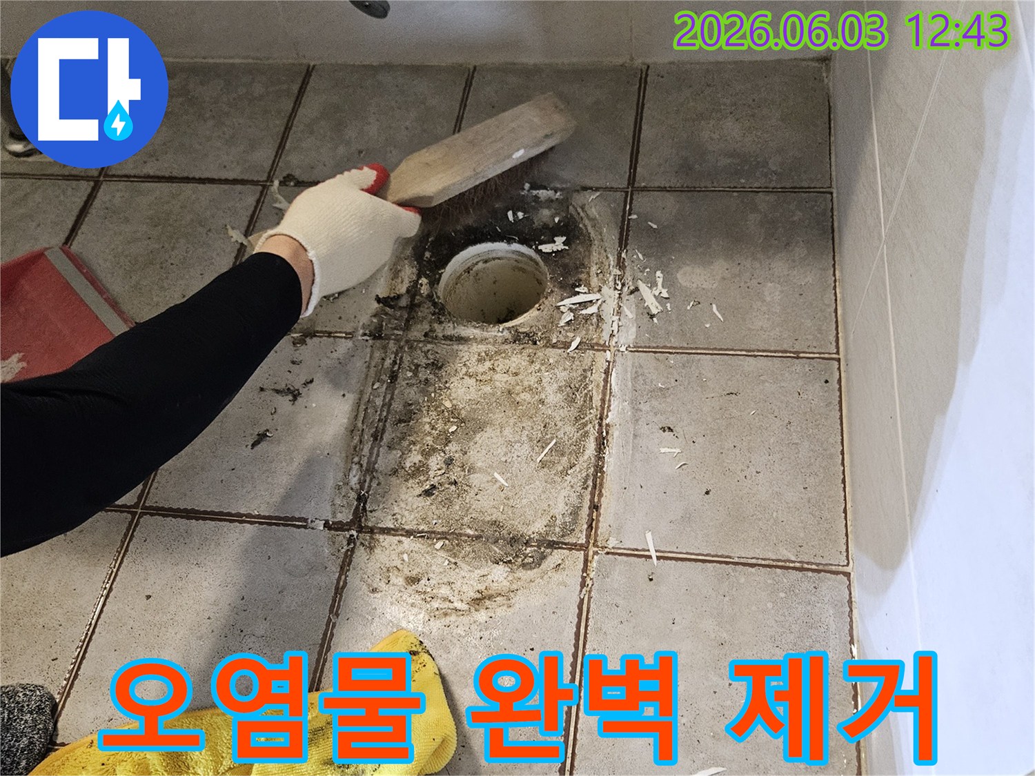 누수 엔지니어가-욕실 바닥의-배수구 주변에-고착된 이물질을-스크래퍼로-정성껏 제거하는-공사 현장 모습