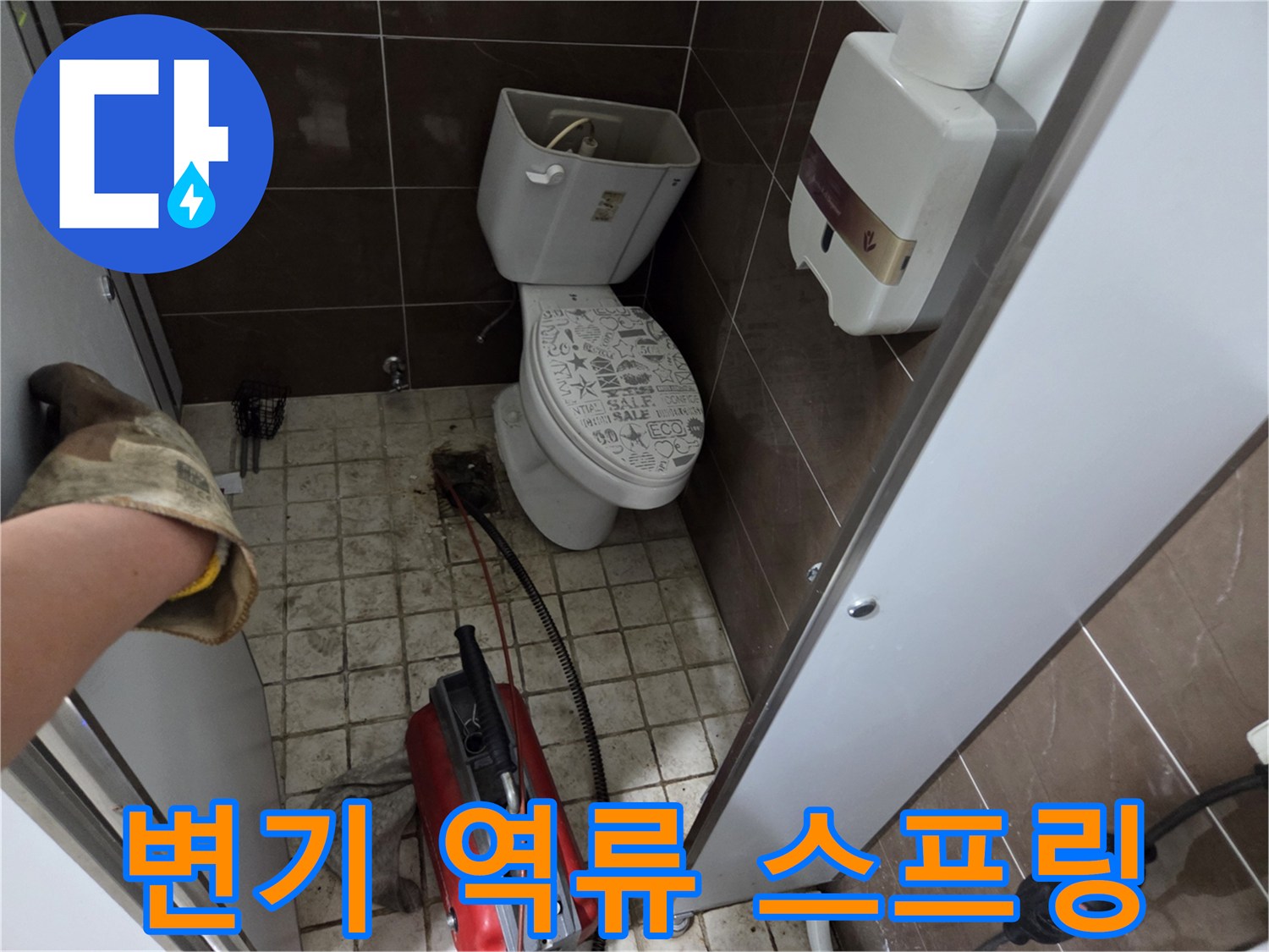 변기 역류 문제를 해결하기 위해-스프링 장비로 배관을 점검하고 뚫는 작업 현장입니다