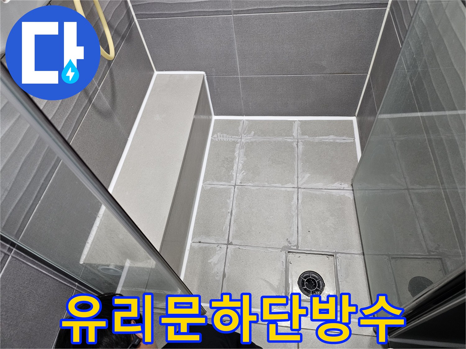 강동구 아파트 샤워실의 유리문 하단에-오래된 실리콘을 제거하고-새로운 방수 실리콘으로 교체하는 모습입니다.