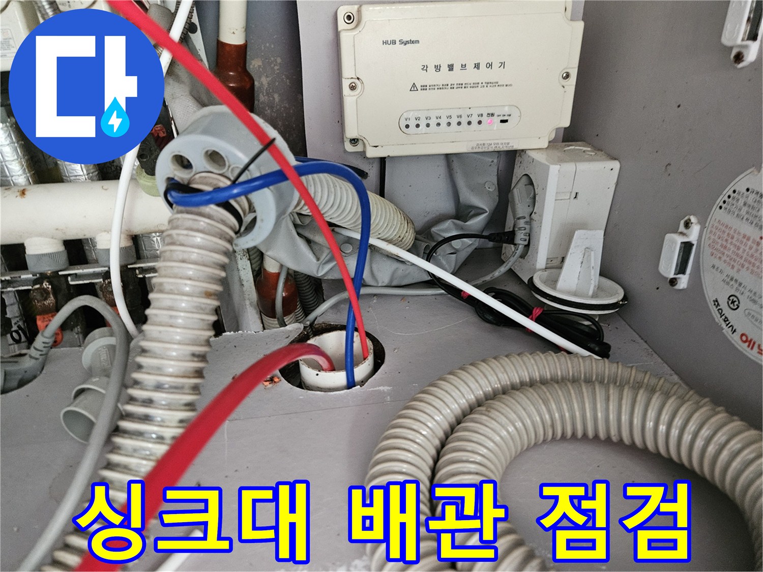 싱크대 하부장 내부의 복잡한 배관과 호스 상태를 보여주는 사진