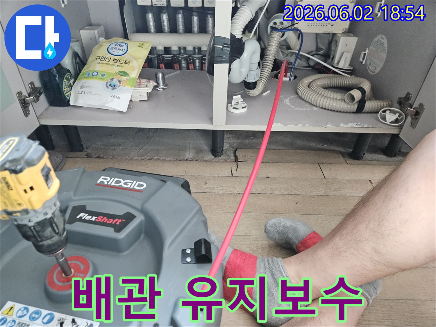 주방 싱크대 아래-배관 막힘을-해결하기 위해-전문 장비를-설치하고-작업을 시작하는 모습입니다.