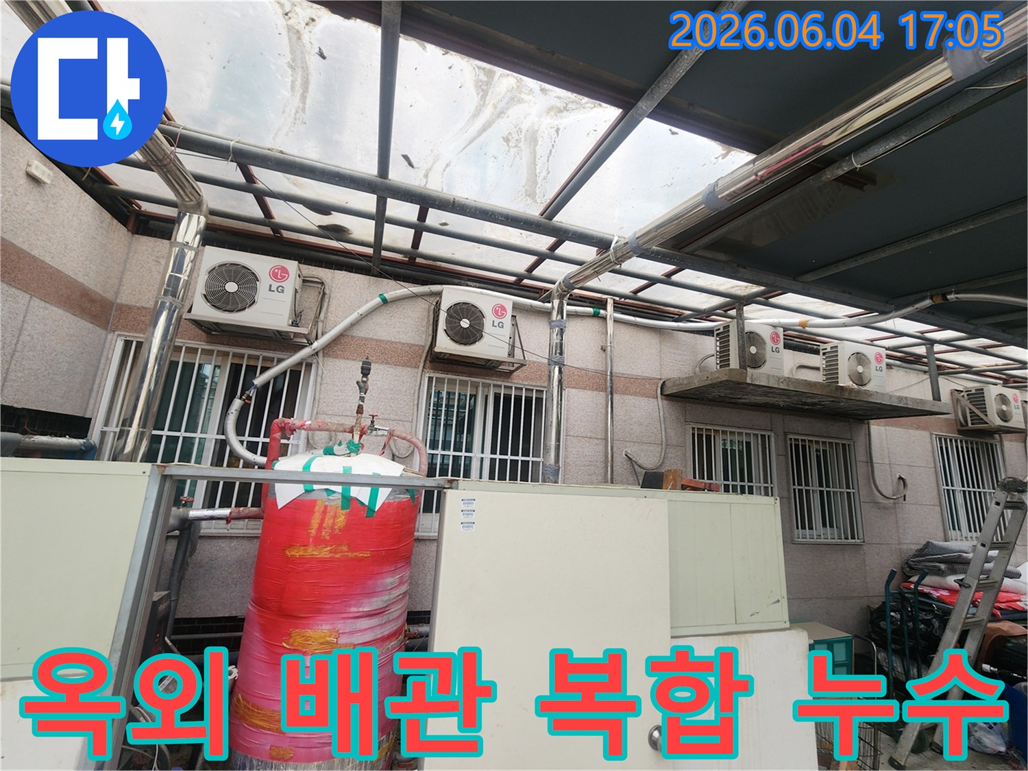 이 이미지는 주택 외부에 설치된-다양한 배관들과-에어컨 실외기-그리고 물탱크가-복잡하게 얽혀있는 모습을 보여줍니다