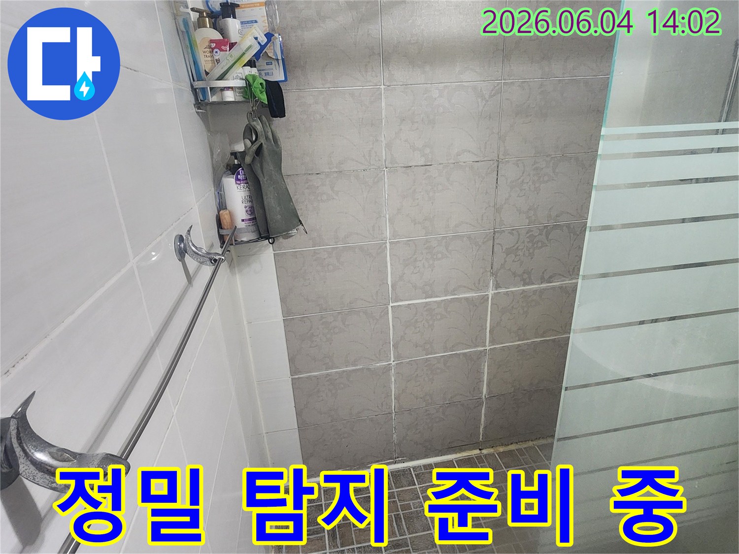 욕실 바닥에 놓인-세면도구와-분리된 샤워봉이-첨단 누수 탐지 장비-설치를 위한-현장 정리 상태를-보여줍니다