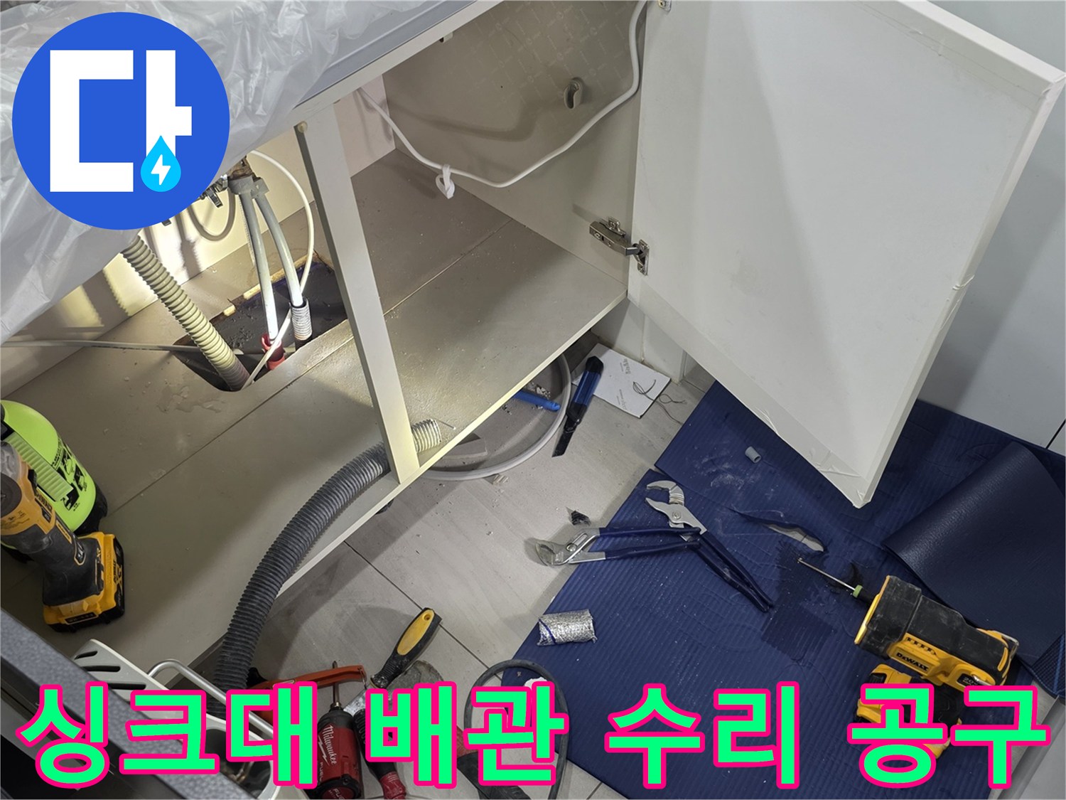 싱크대 밑 배관 근처에 놓인 전동 드릴과 절단 장비
