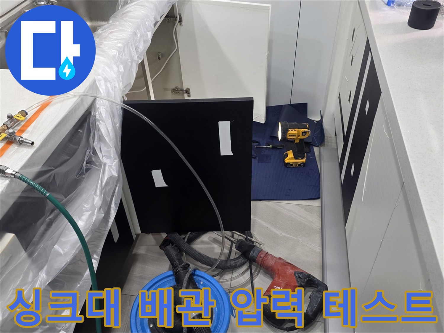 주방 싱크대 하단 배관에 압력계를 연결하여 공압 테스트를 진행하는 모습입니다.