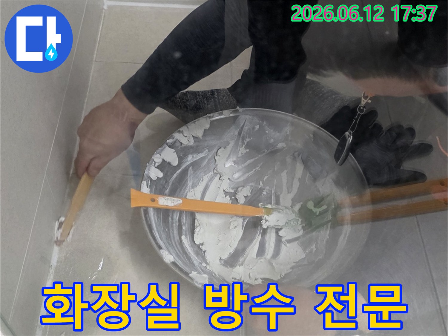 누수 전문가가 화장실 누수 흔적을 발견하고-타일 틈새에 방수재를 도포하여 문제를 해결하고 있습니다
