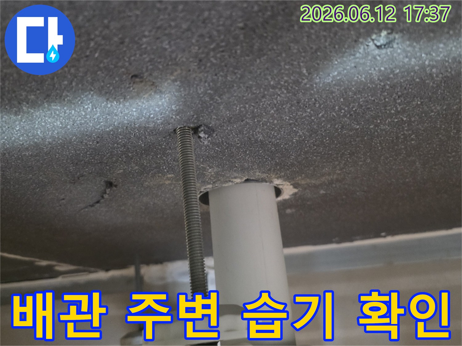 천장 배관 주변에-스며든 습기를-정밀하게-확인하며-누수 여부를-판단하는 모습