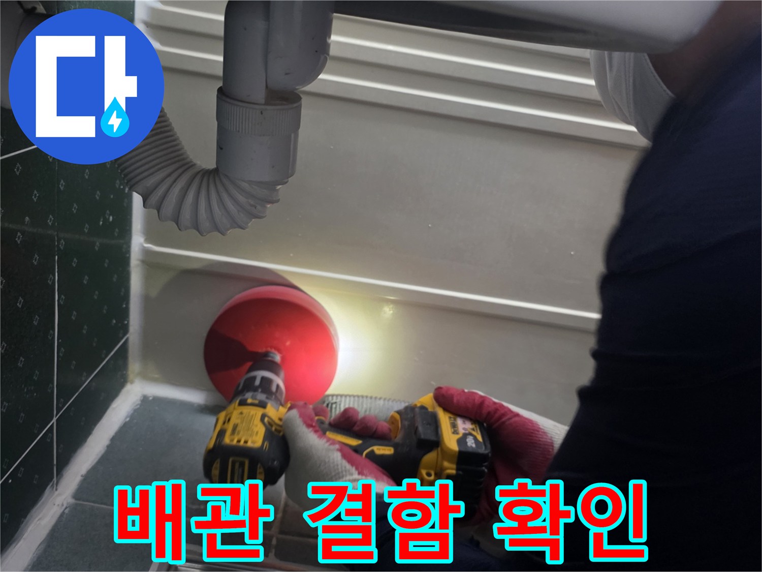 전동 드릴과 조명을 사용하여 배관 틈새를 조사하는 모습