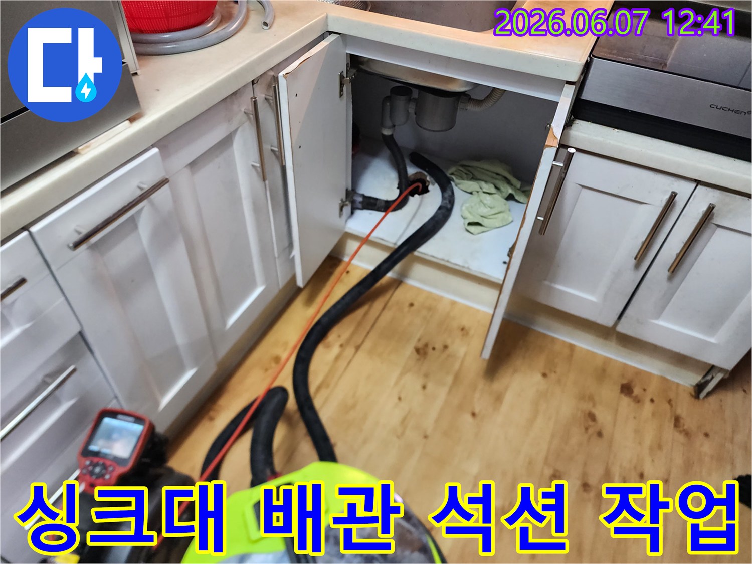 싱크대 하부 배관의 고인 물을 제거하기 위해 석션기를 사용하는 모습입니다.