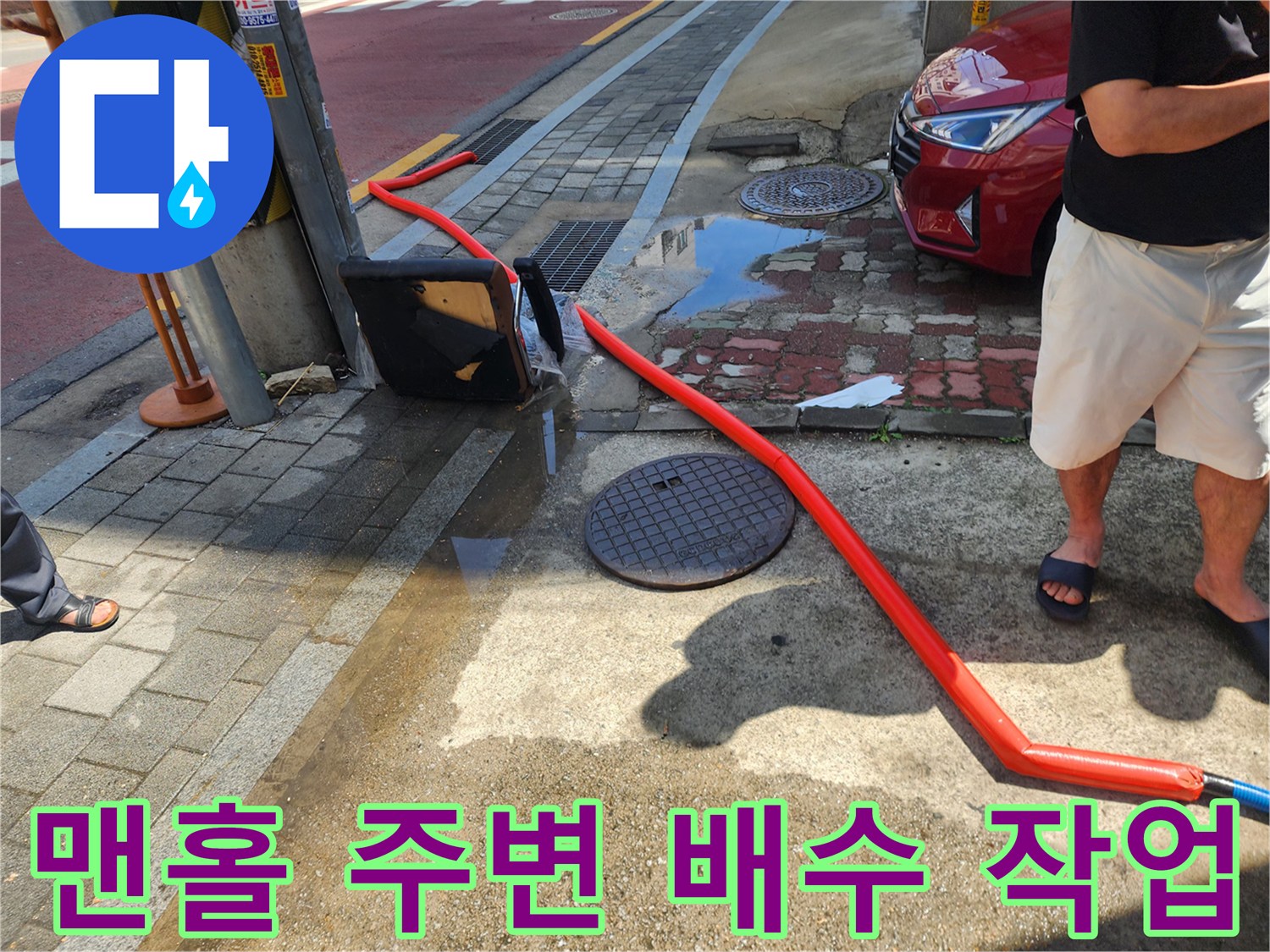 도로-측면-맨홀-주변의-역류한-물-제거-중