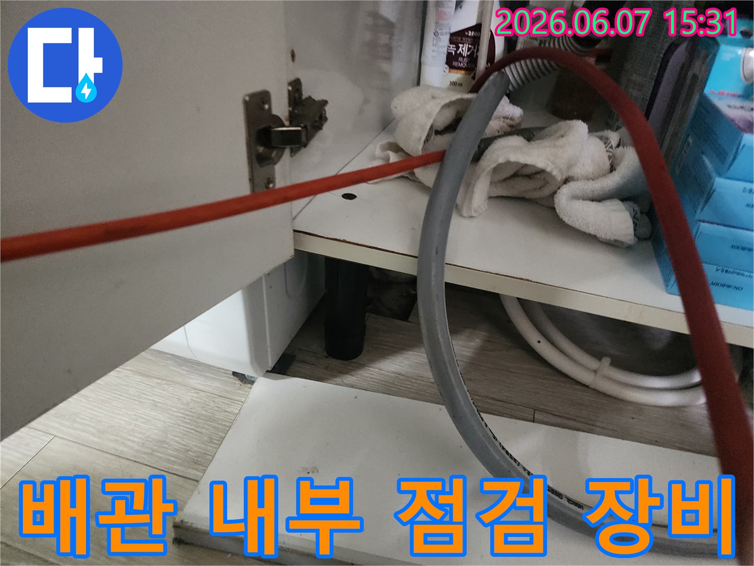 싱크대 아래 배관 주위에 놓인 작업용 호스 및 도구