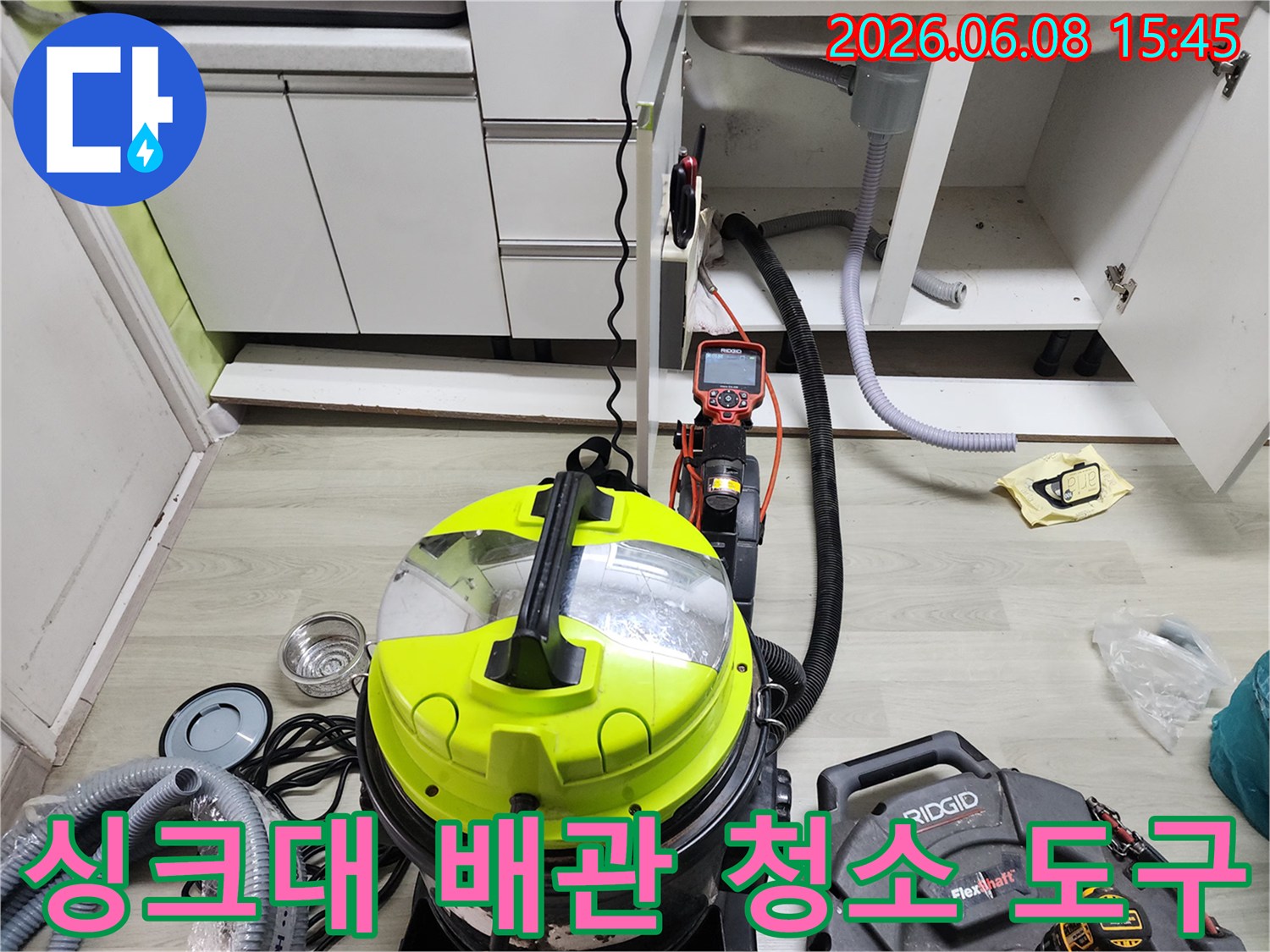 싱크대 아래 하수구 작업을 위해 배치된 석션기와 각종 호스들