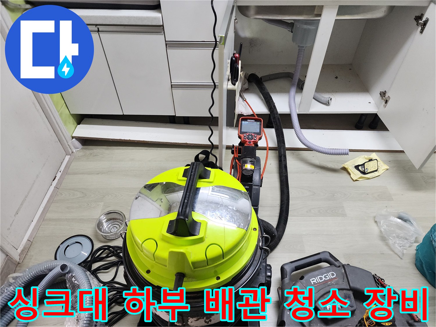 싱크대 하부장 내부의 배수 호스와 석션기 흡입 호스가 연결된 현장 상황