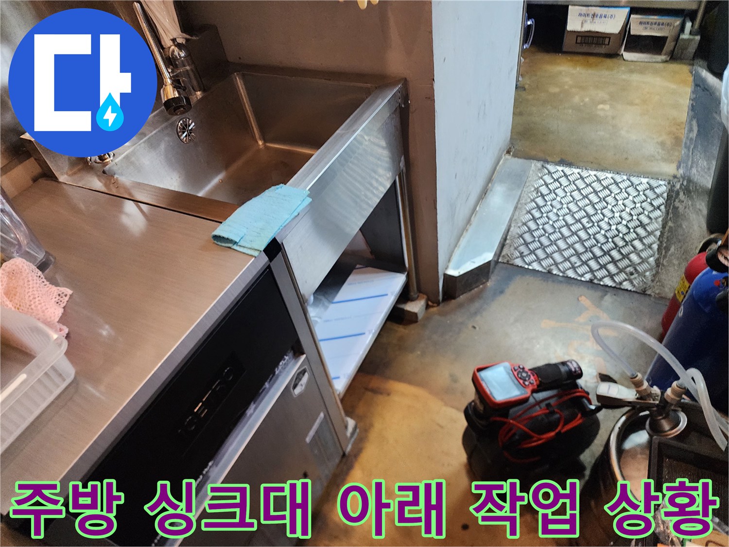 스테인리스 싱크대 하단과 바닥에 놓인 전문 배관 장비