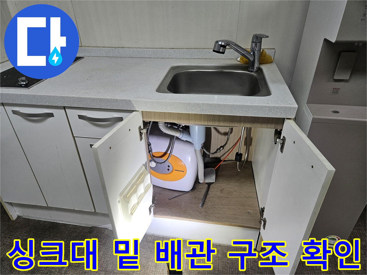 주방 싱크대 아래 수납 공간 내 세탁기 연결 배관 모습