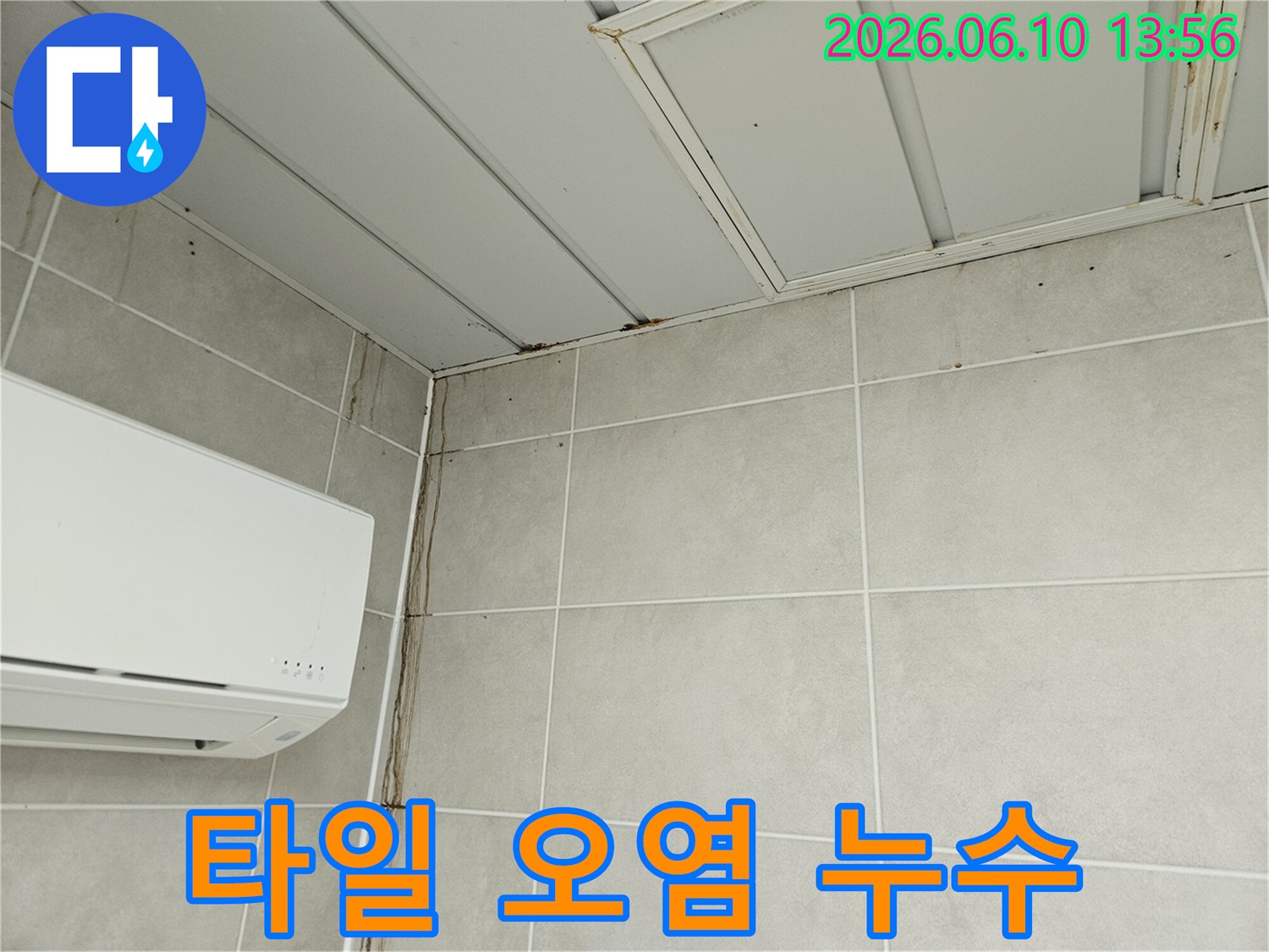 타일 벽면을 따라 길게 흘러내린 누수 자국과 천장 모서리의 곰팡이-누수로 인한 심각한 벽면 오염