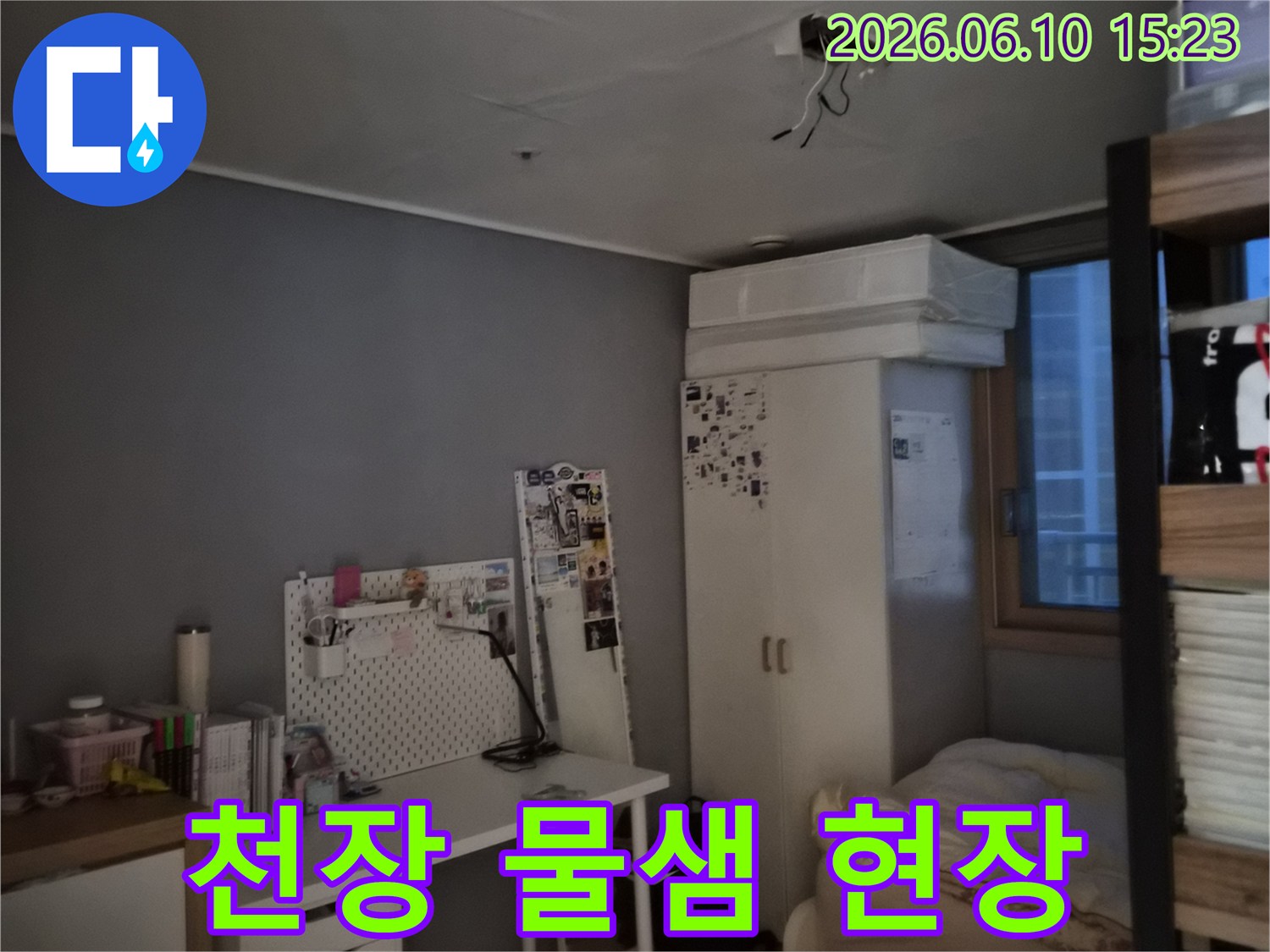방 천장에 물이 새어 얼룩이 지고 전선이 노출된 모습-누수와 전기 안전 문제가 우려되는 상황