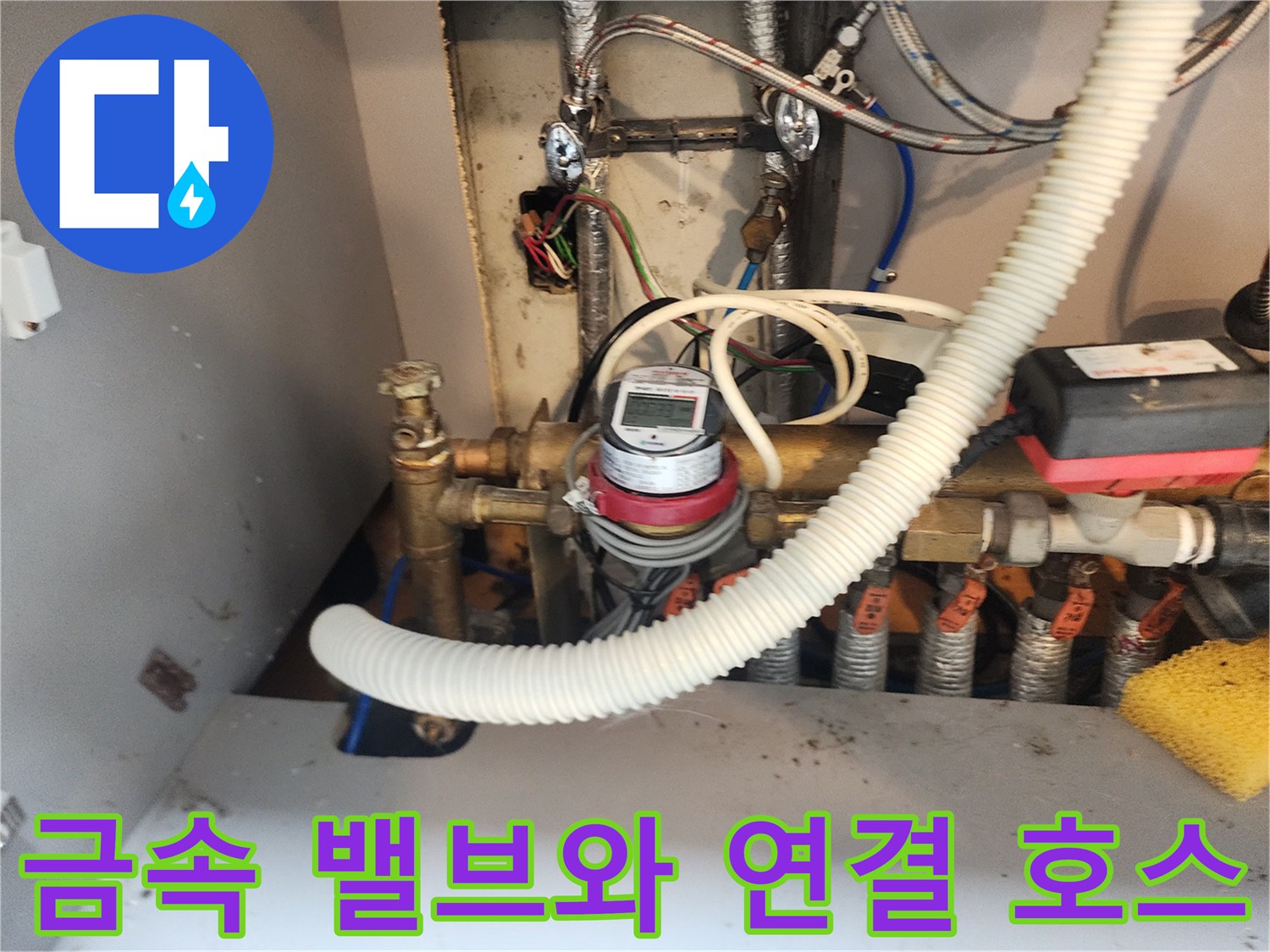 싱크대 하부의 금속 부품과 유량계가 보이는 배관 시설