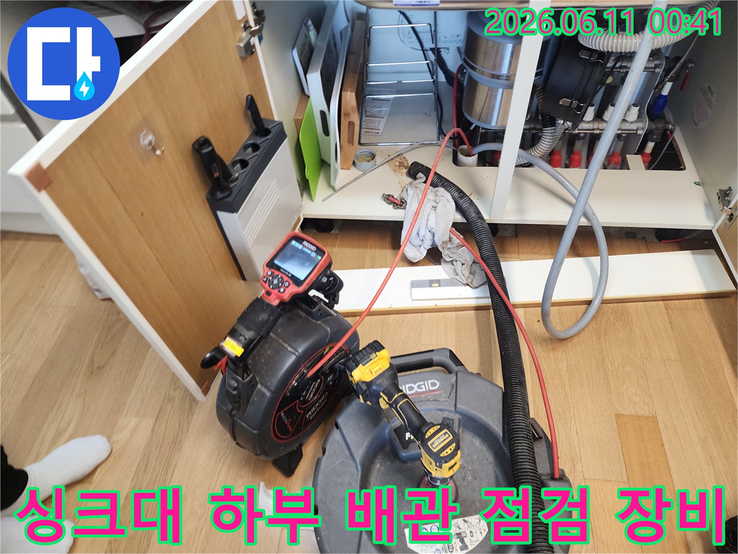 싱크대 아래쪽 좁은 공간에 배치된 배관 내시경 카메라와 석션기 작업 현장입니다.