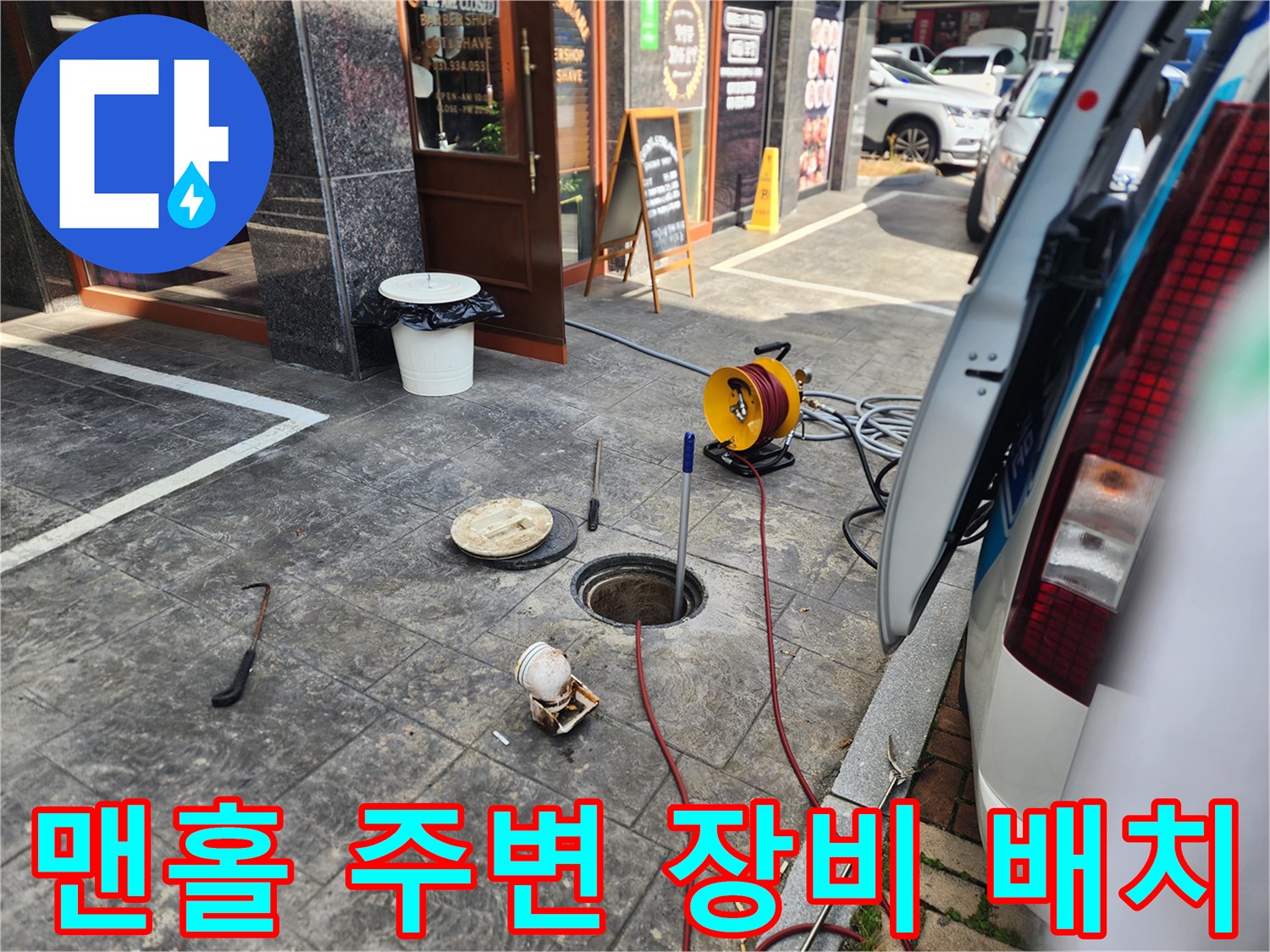 작업을 위해 맨홀 근처에 배치된 고압 세척기 릴과 연결 호스 모습