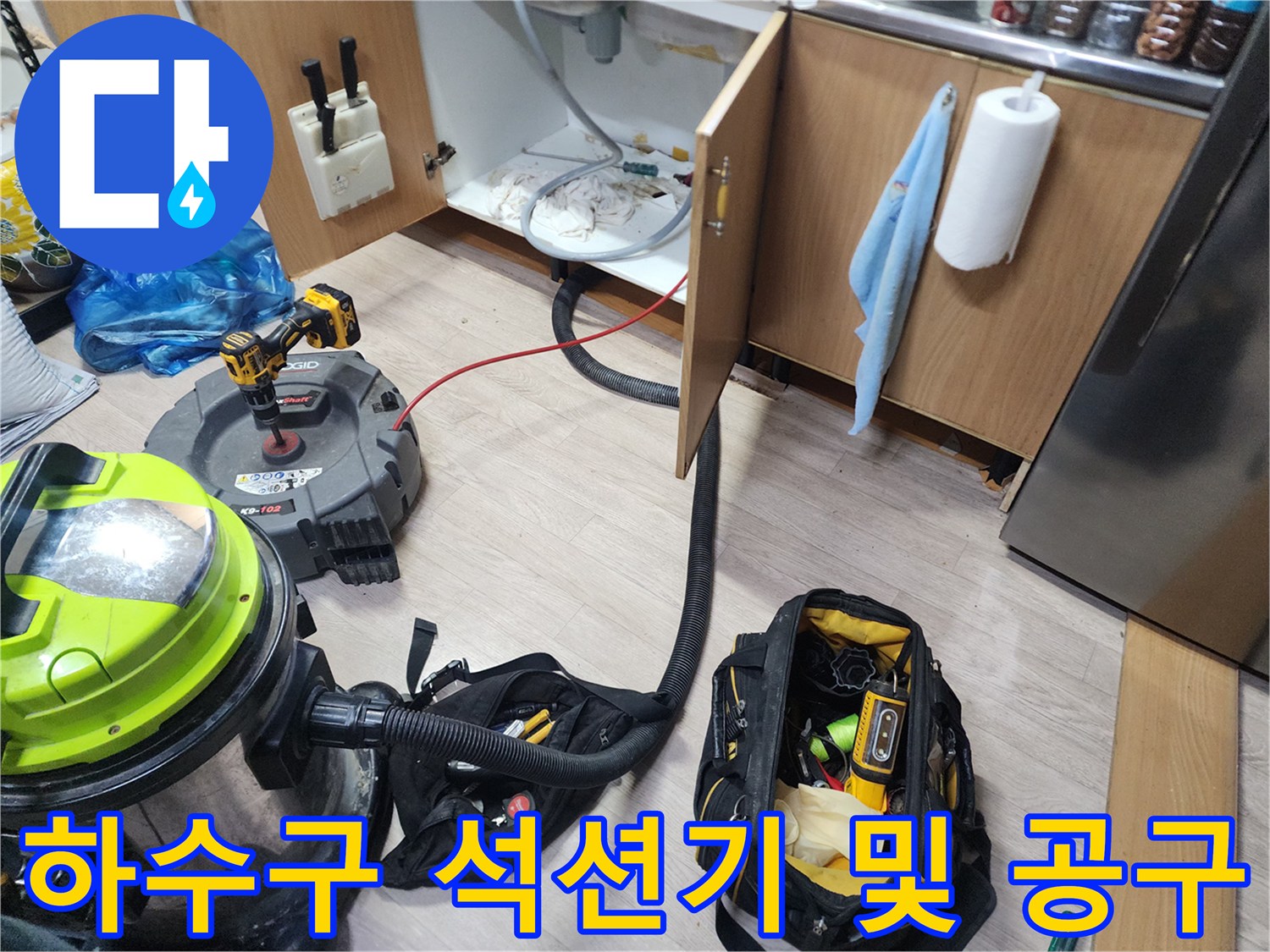 싱크대 밑 작업 공간에 놓인 대형 석션기와 배관 청소용 수공구들
