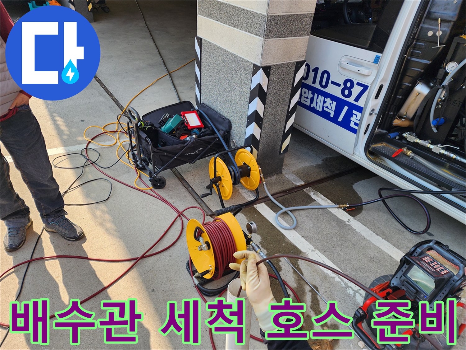 바닥에 배치된 노란색 릴과 연결된 고압 세척 호스