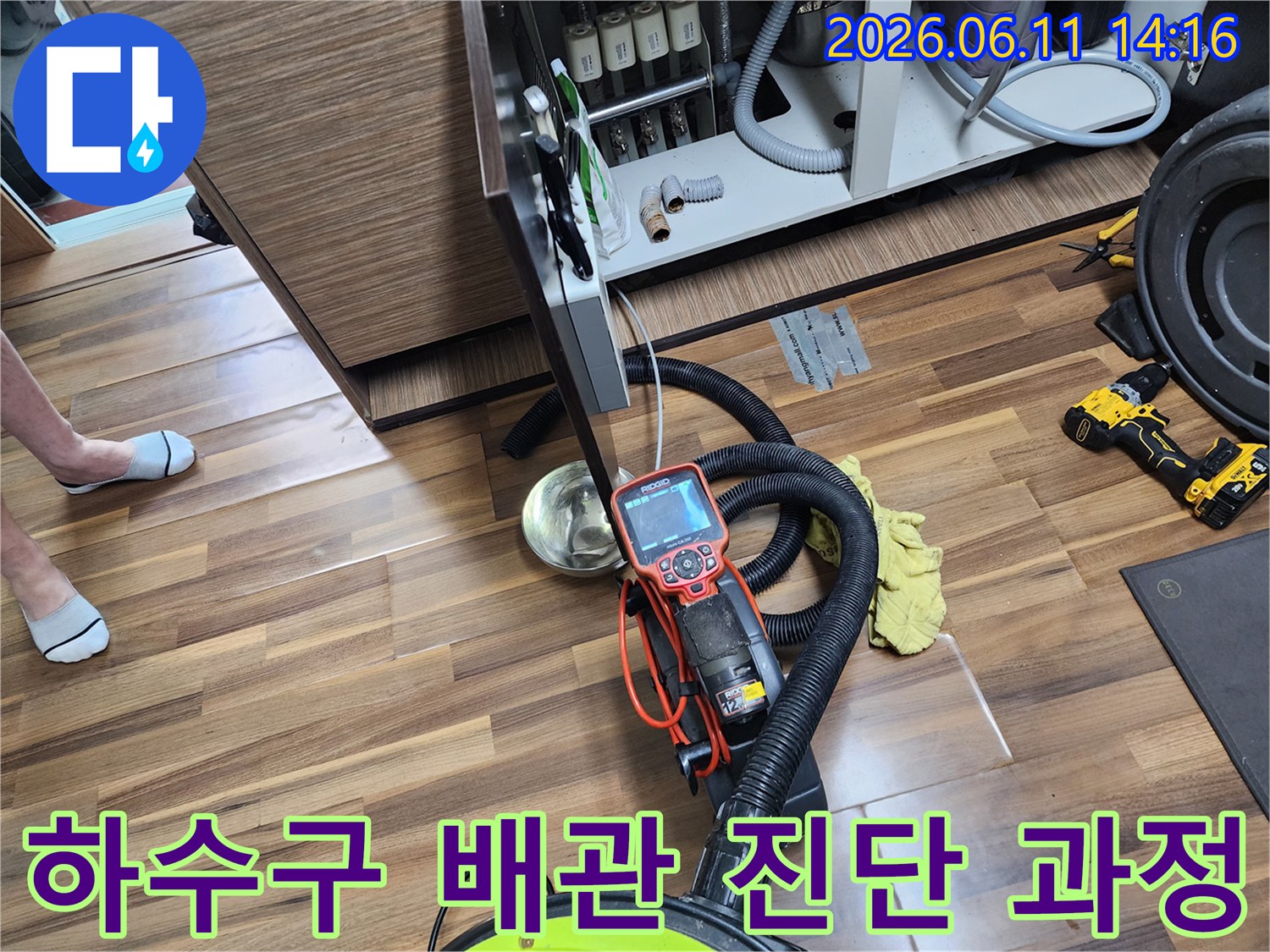 싱크대 하부장 아래에서 진행되는 배관 내시경 검사와 석션 장비의 모습입니다.