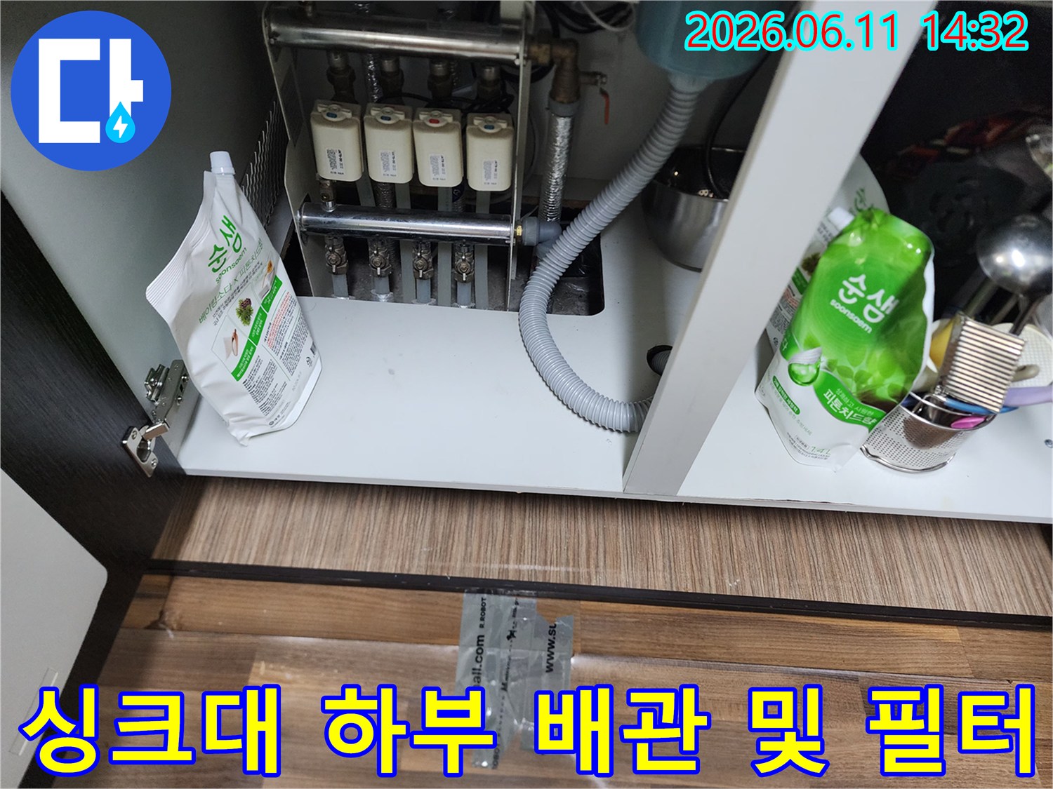 정수기 필터와 급수 밸브가 연결된 싱크대 하부장 내부 사진
