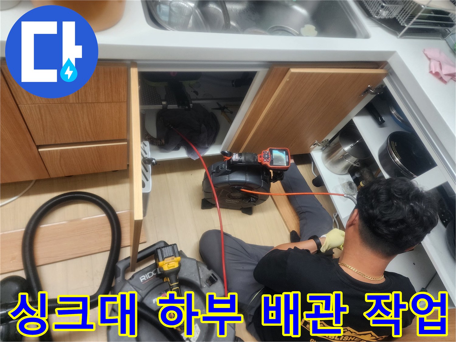 작업자가 싱크대 밑 공간에서 배관 내시경 장비를 조작하는 장면