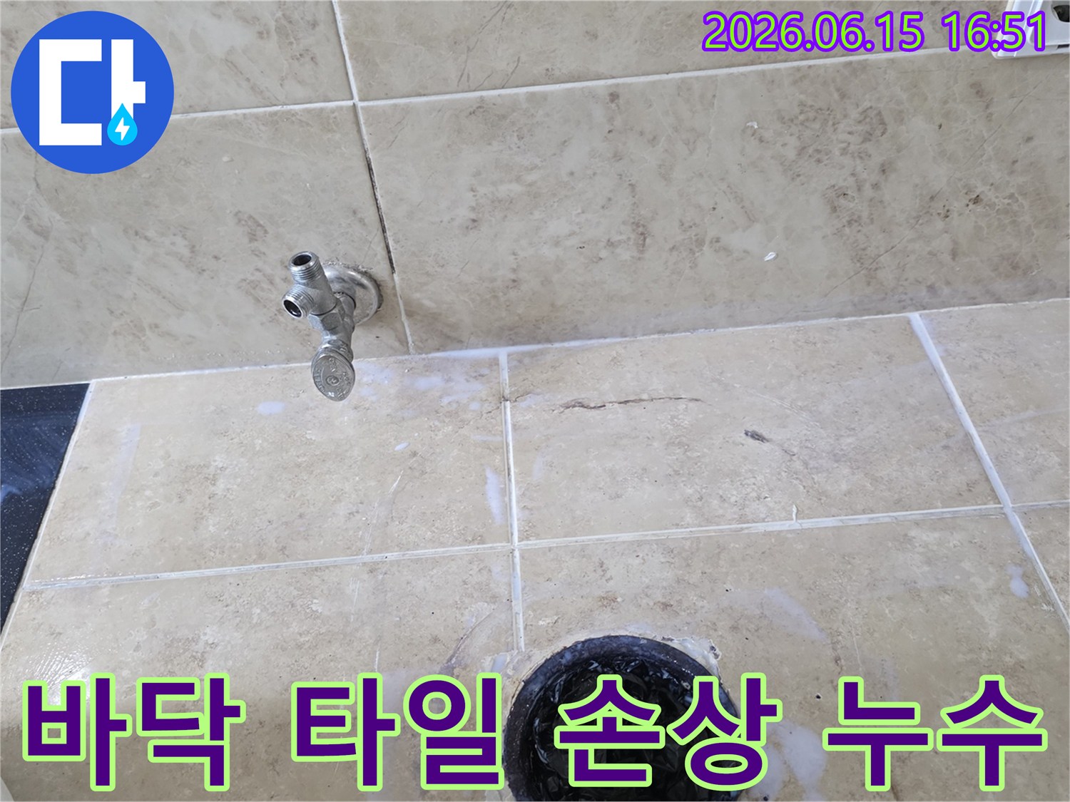 욕실 바닥 타일에 생긴 균열과-그 주변으로 물이 스며든 흔적-그리고 수도꼭지 및 배수구의 모습을 담은 사진입니다