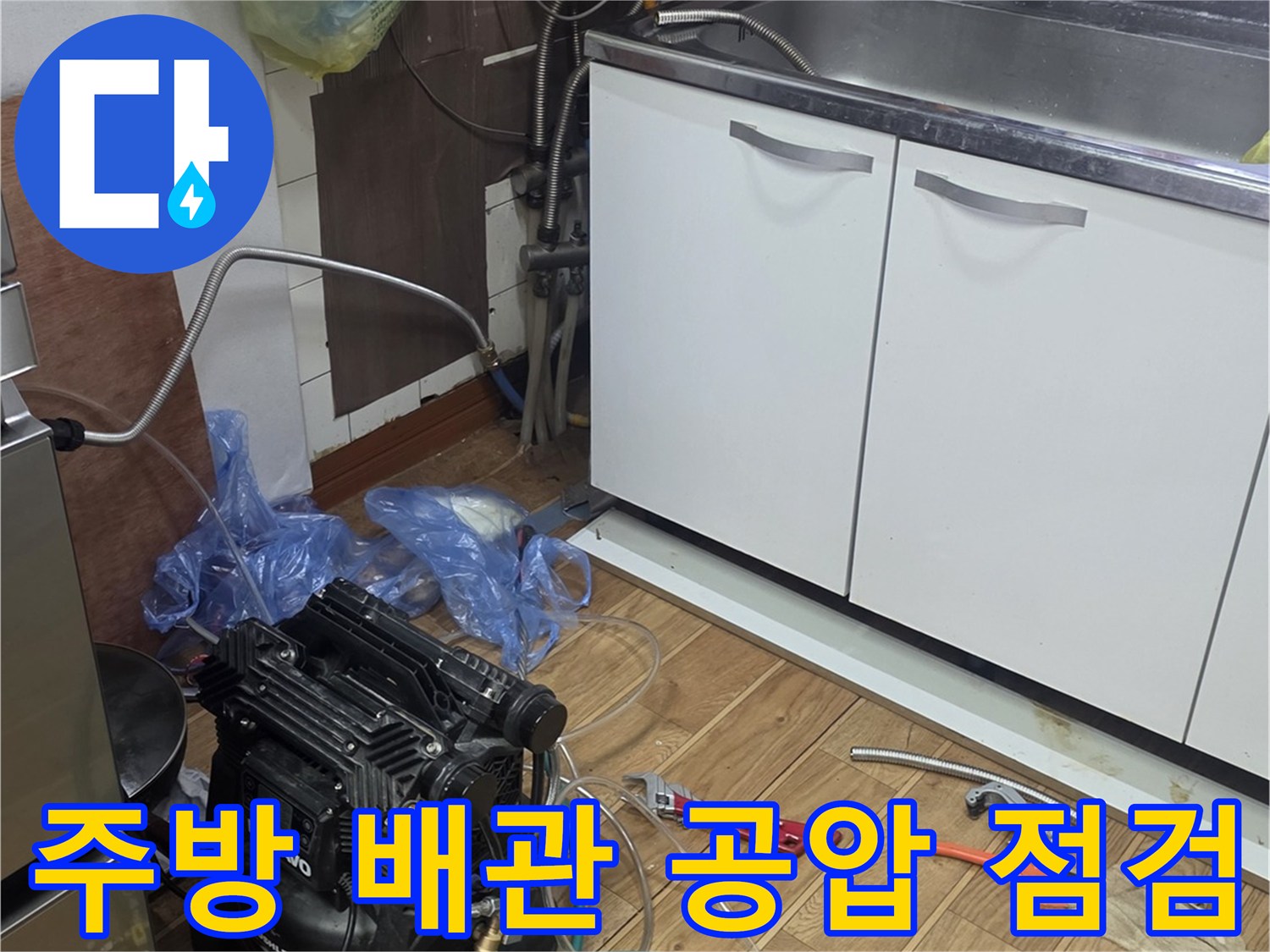 주방 싱크대 하부장 아래 설치된 공기 압축기와 배관 압력 측정 장비