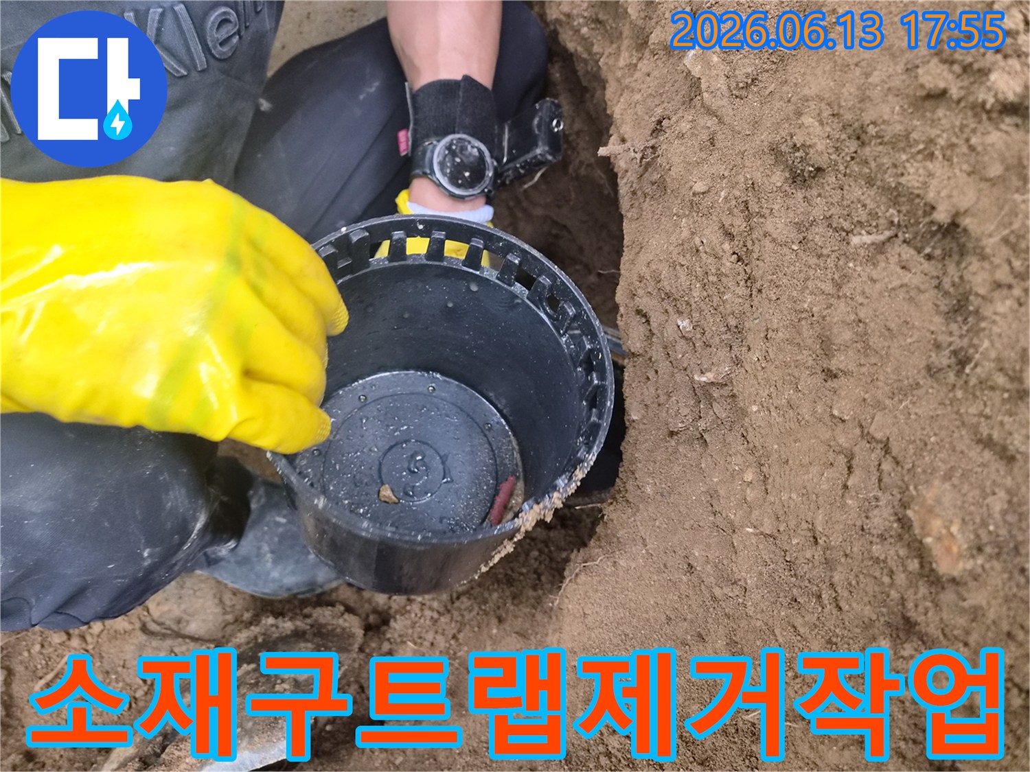 노란색 장갑을 낀 작업자가 흙 속에서 꺼낸 소재구 트랩을 점검하는 모습