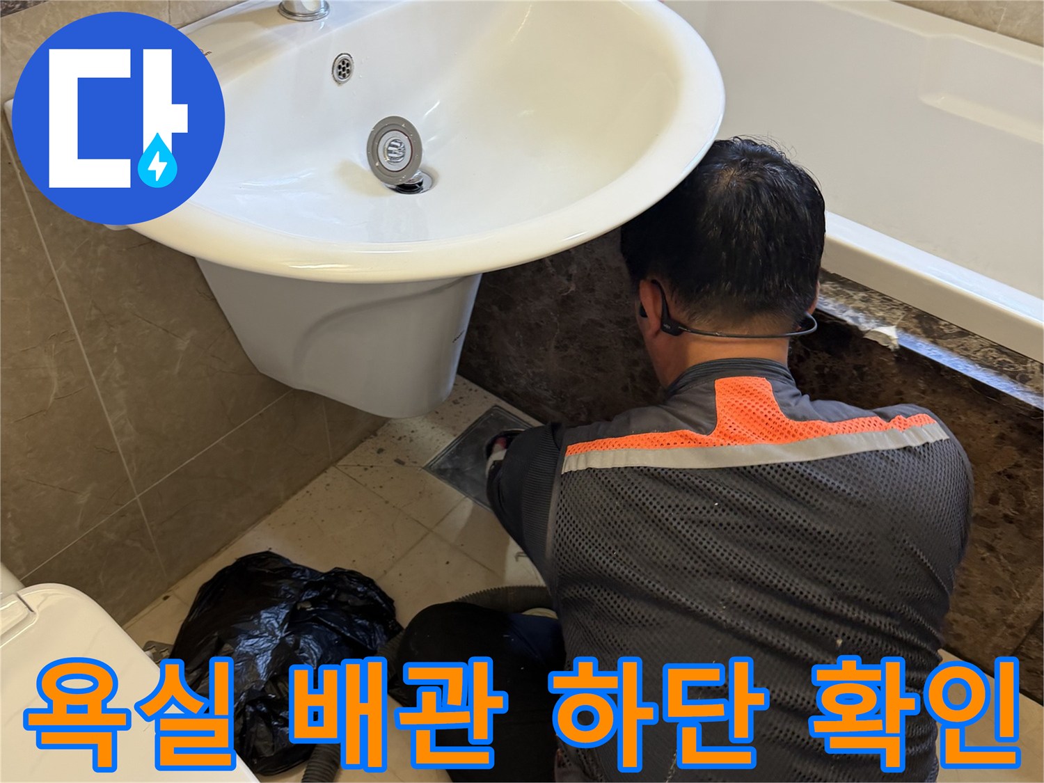 세면대 아래쪽 배수구 부위를 육안으로 검사하는 엔지니어입니다.