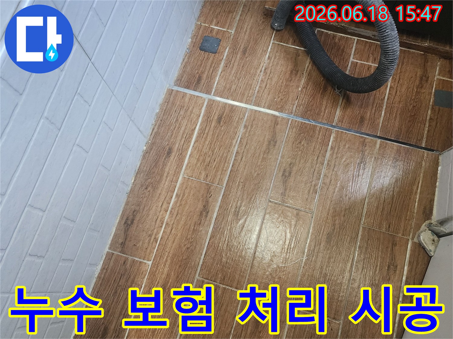 염창동 아파트에서 누수 보험 처리를 위한 상담부터 시공까지 진행 중인 현장 사진입니다-바닥 타일 위에 검은색 호스가 놓여 있습니다.