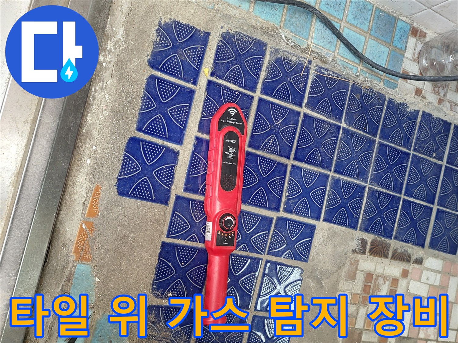 푸른색 패턴 타일 위에 놓여 있는 빨간색 누수 탐지기