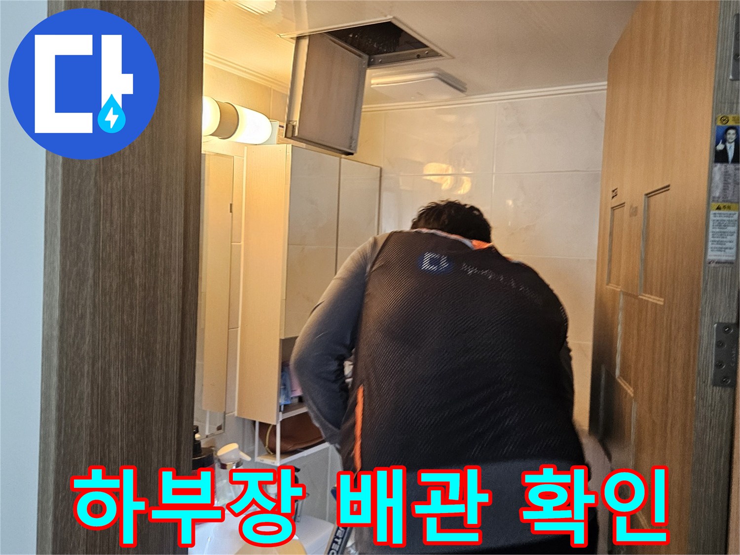 작업자가 싱크대 아래쪽 배관 구조를 점검하는 모습입니다