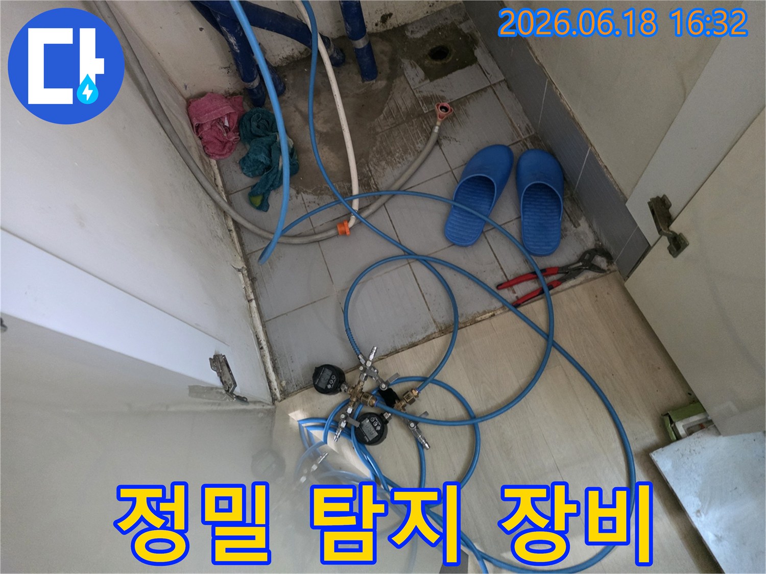 이 이미지는 누수 탐지를 위한-압력 게이지와-파란색 호스 등-전문 장비들이-설치된-현장을 보여줍니다.
