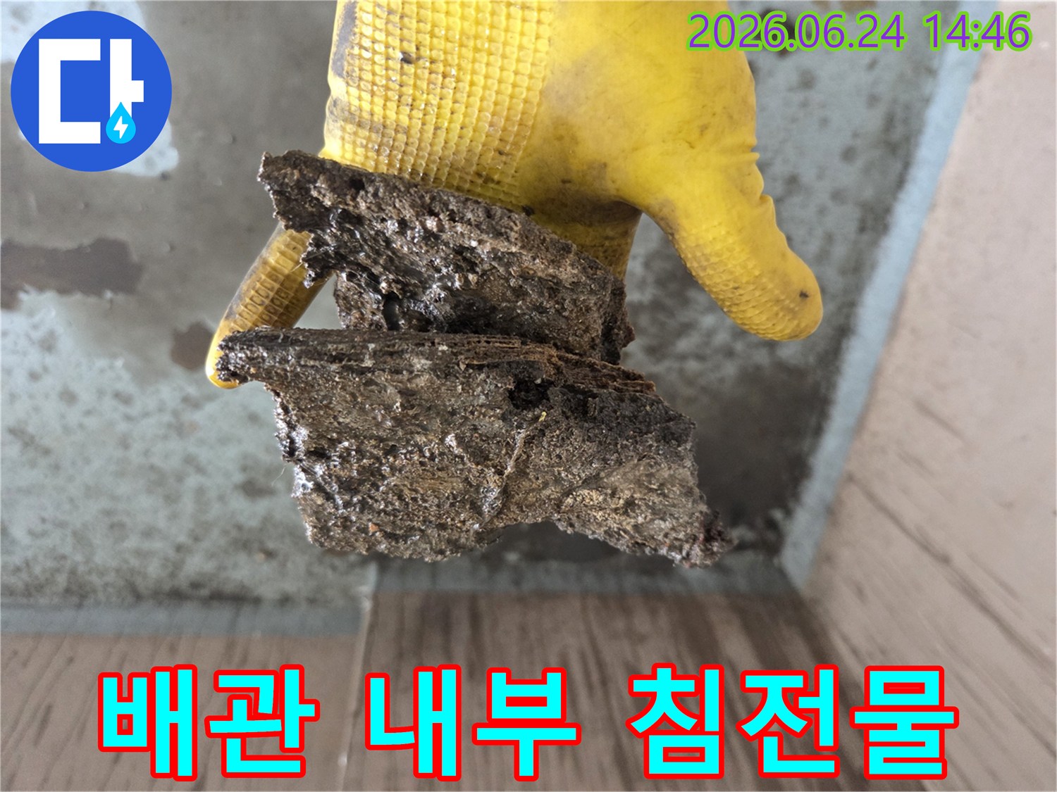 배관-공사-도중-발견된-오래된-배관의-부식된-잔해물을-노란-장갑을-낀-손으로-들고-있는-모습입니다.