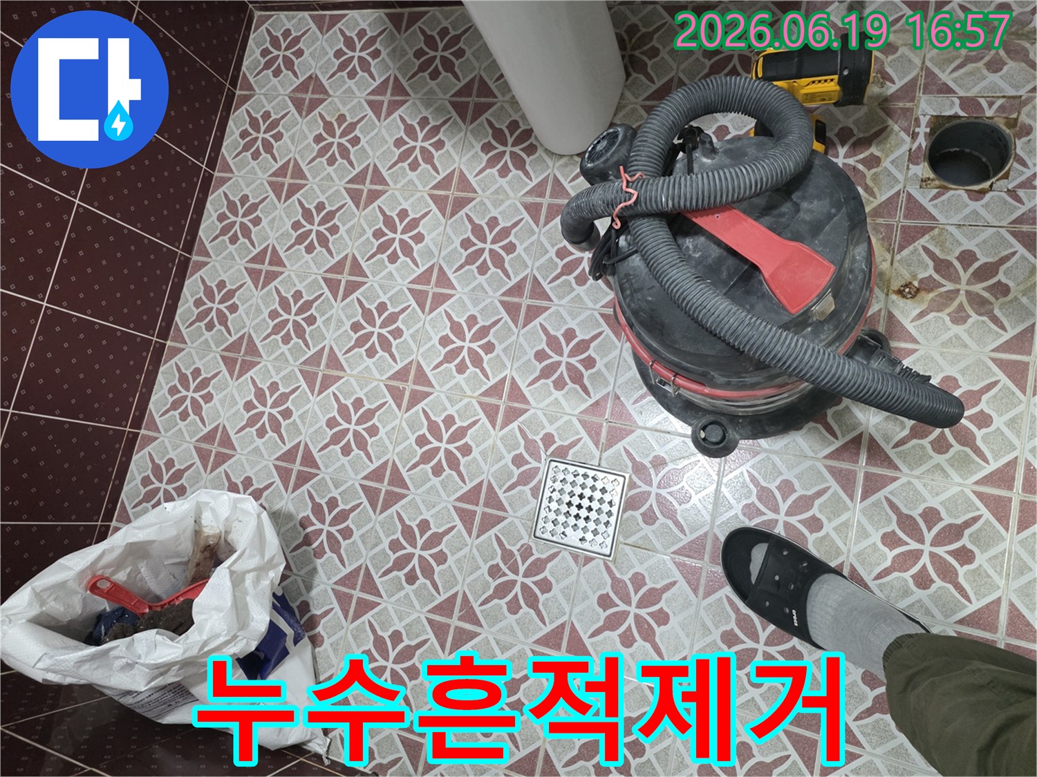 누수 탐지 완료 후-욕실 바닥에 놓인 습식 청소기와-배수구-그리고 작업 중 발생한 폐기물이 담긴 봉투