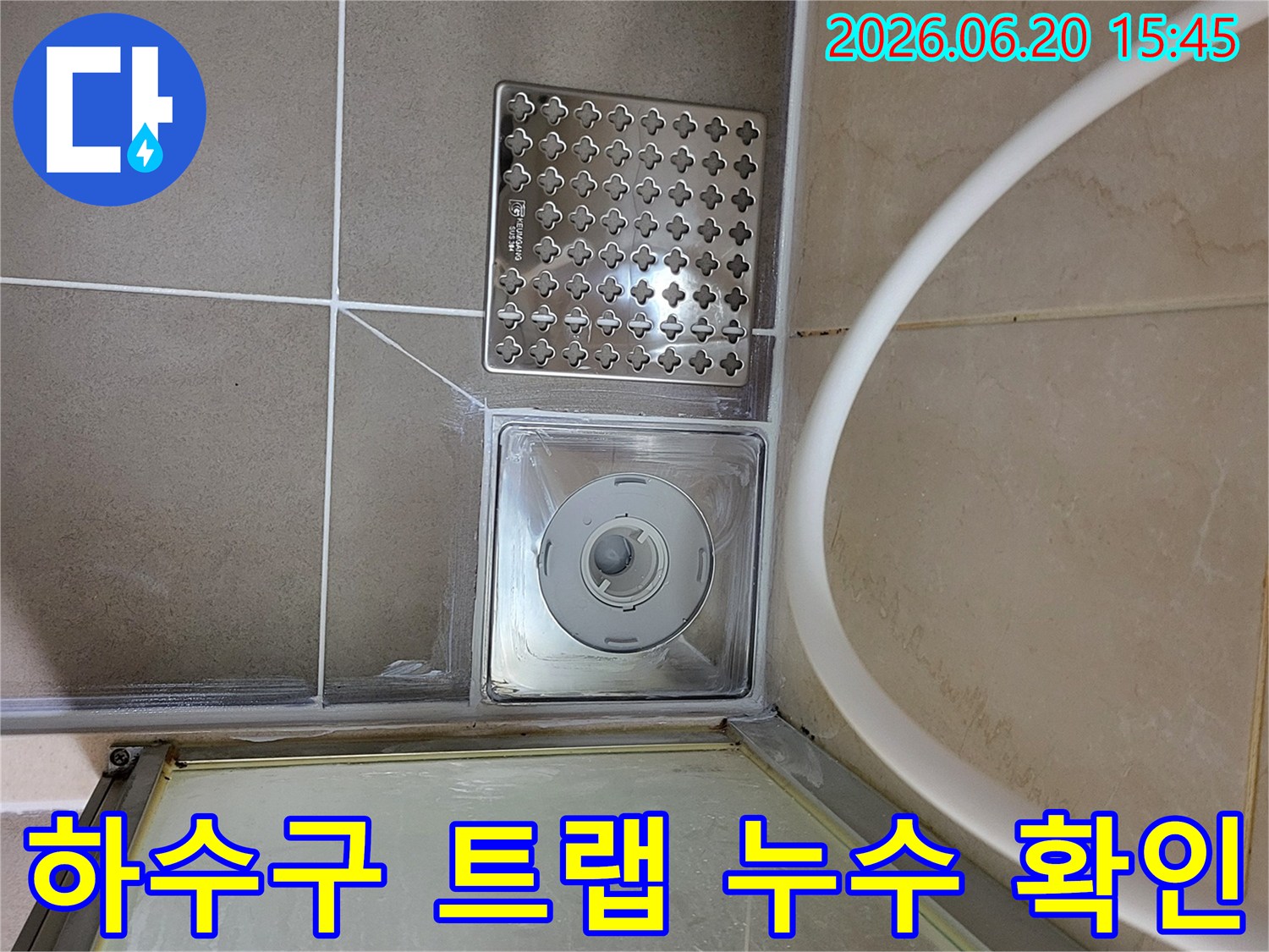 욕실 바닥의 하수구 트랩과 일반 배수구-주변 타일과 줄눈 상태를 함께 보여주며-누수 점검의 중요성을 강조합니다.