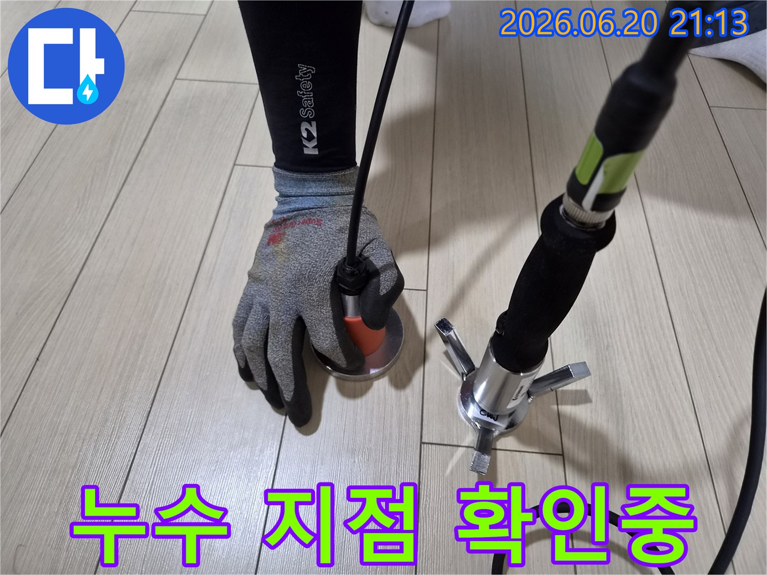 누수-전문가가-바닥-타일에-귀를-기울여-청음식-탐지기로-누수-위치를-정확히-파악하는-모습