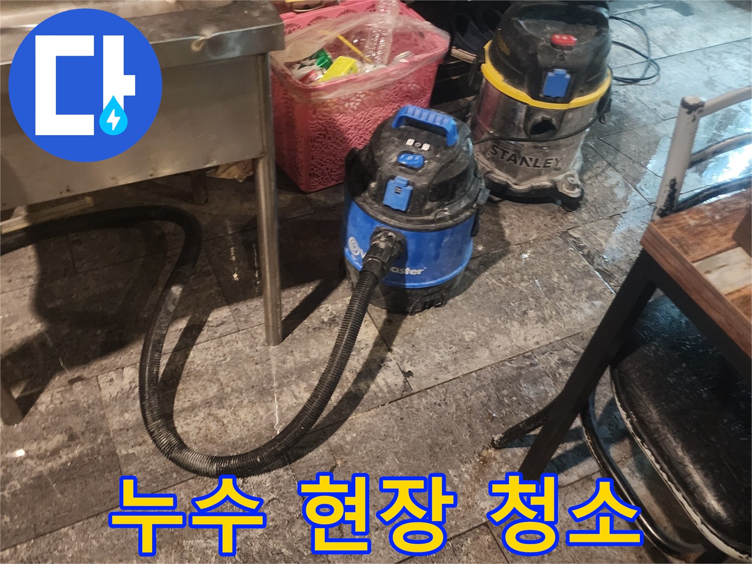 누수 피해 현장에서-바닥에 고인 물을-신속하게 제거하고-건조시키기 위해-사용되는-전문 석션 장비 두 대가-작업 준비를 마친 모습입니다.
