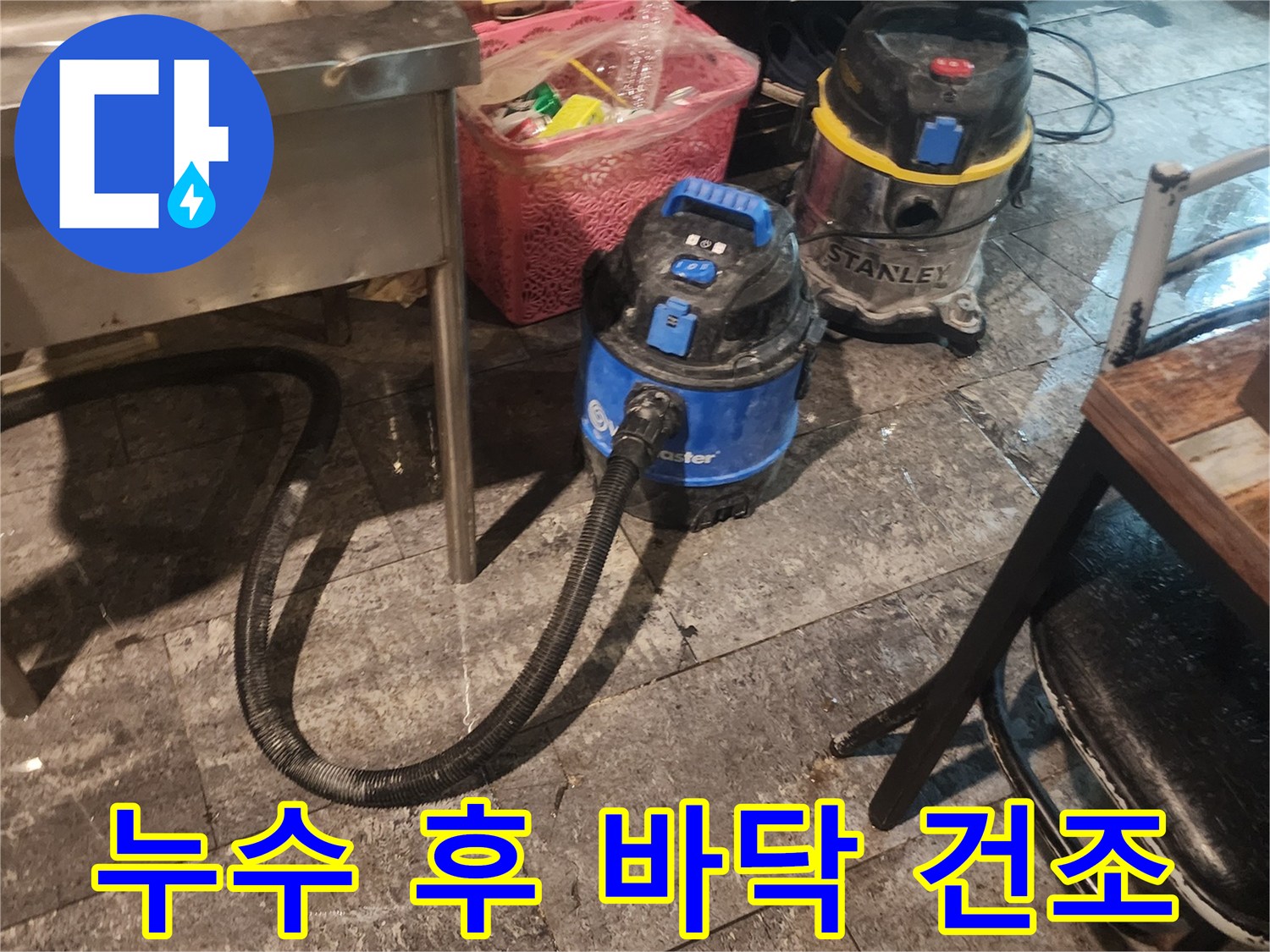 누수 현장에서-바닥에 고인 물을-빠르게 흡수하고-제거하기 위해-사용되는-산업용 청소 장비 두 대가-작동 중인 모습입니다.