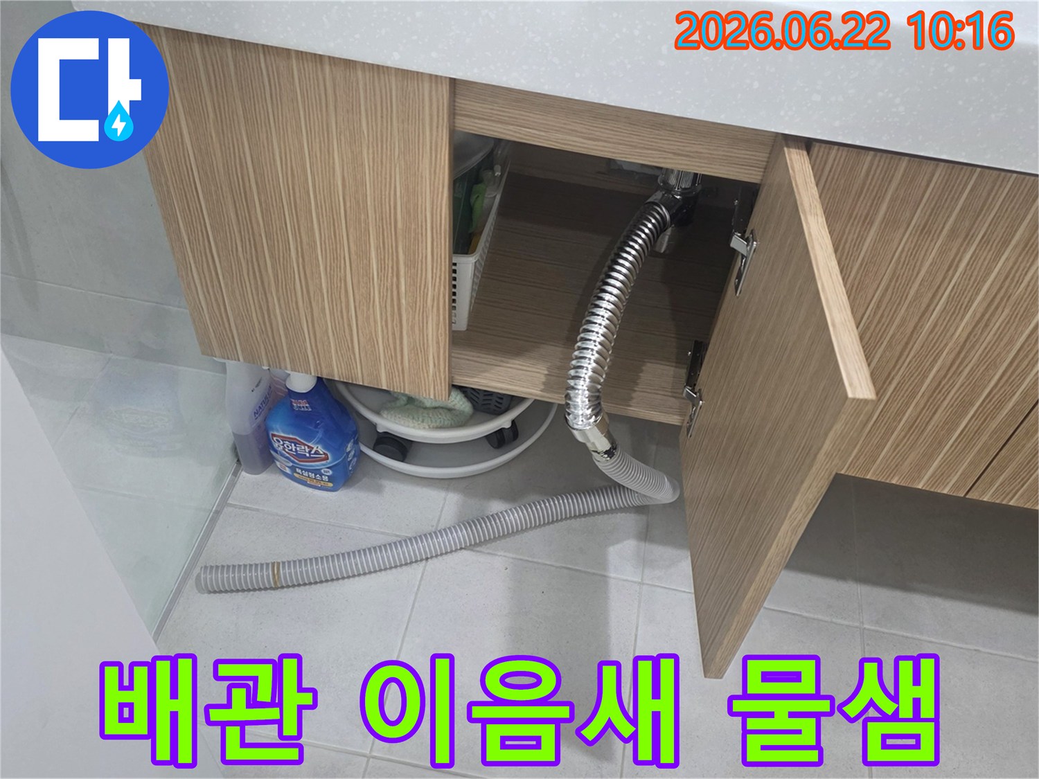 세면대 하부장 내부에서 배수관 이음새가 헐거워져 물이 새는-누수 현장을 정밀하게 점검하는 모습