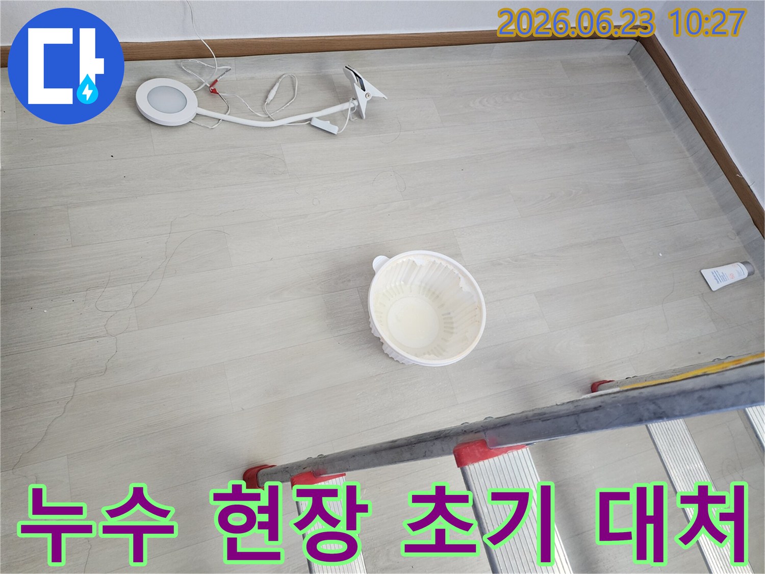 천장에서 물이 떨어져 바닥에 놓인 물받이 그릇과-누수 지점 확인을 위한 사다리-작업용 조명 장비가 함께 보이는-누수 공사 전 현장 모습입니다
