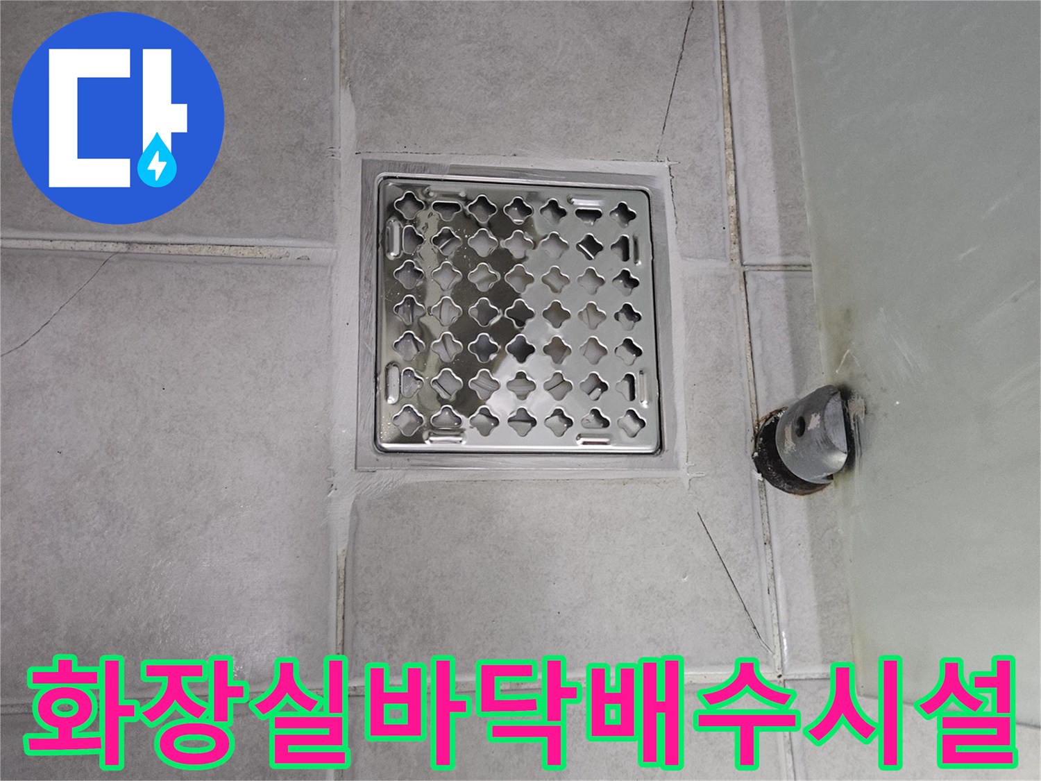 금이 간 타일과 노출된 하수도 배관의 근접 사진입니다.